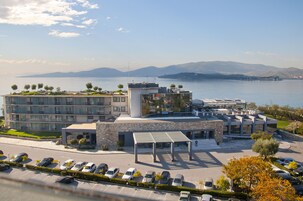 Ένα σύγχρονο ξενοδοχείο με χώρο στάθμευσης, σκεπαστό εξωτερικό χώρο και θέα σε μια λίμνη και σε βουνά.