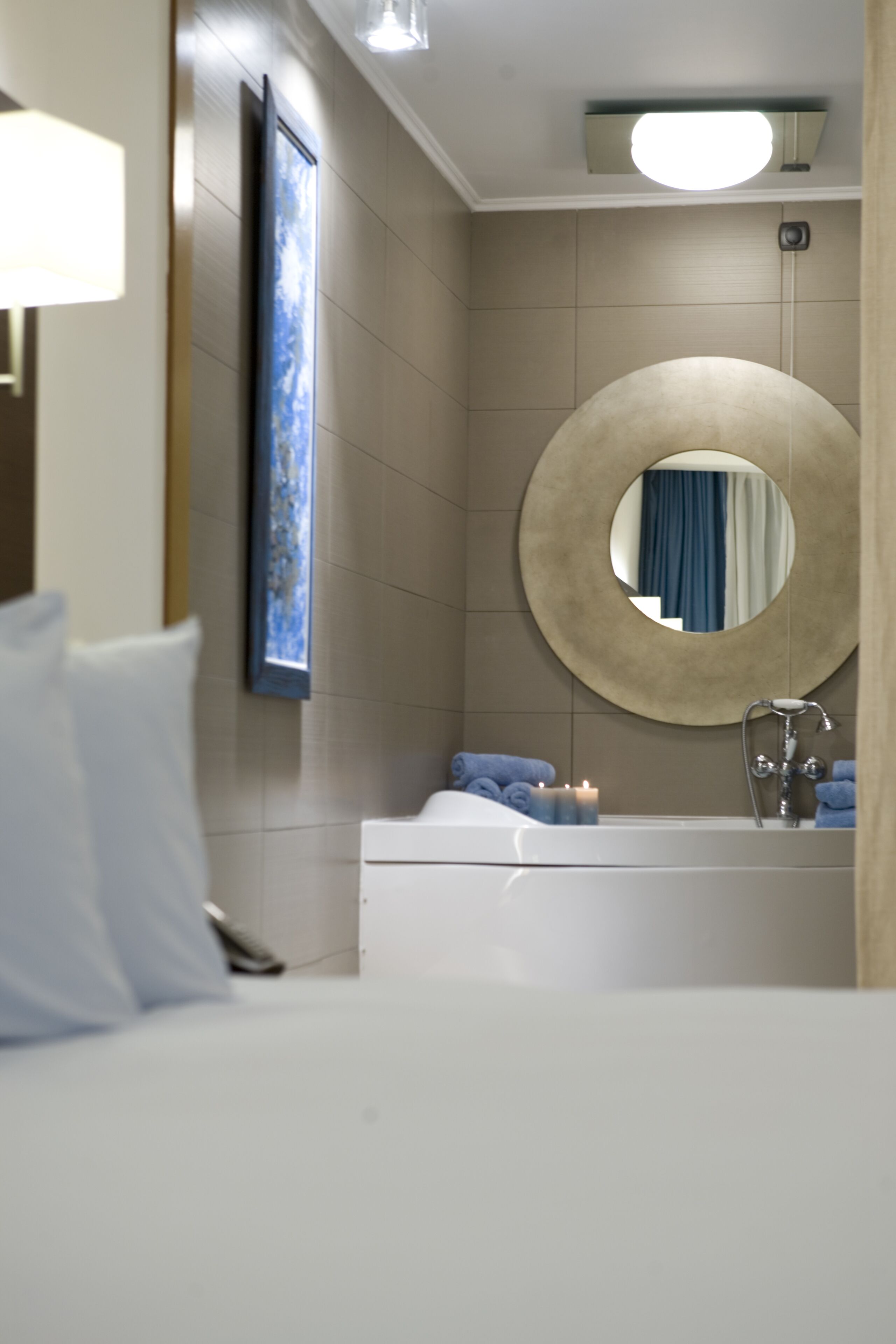 Een moderne badkamer met een badkuip, een ronde spiegel en een wandlamp.