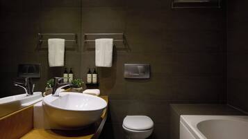 A modern bathroom with a large white sink, a toilet, and a bathtub.