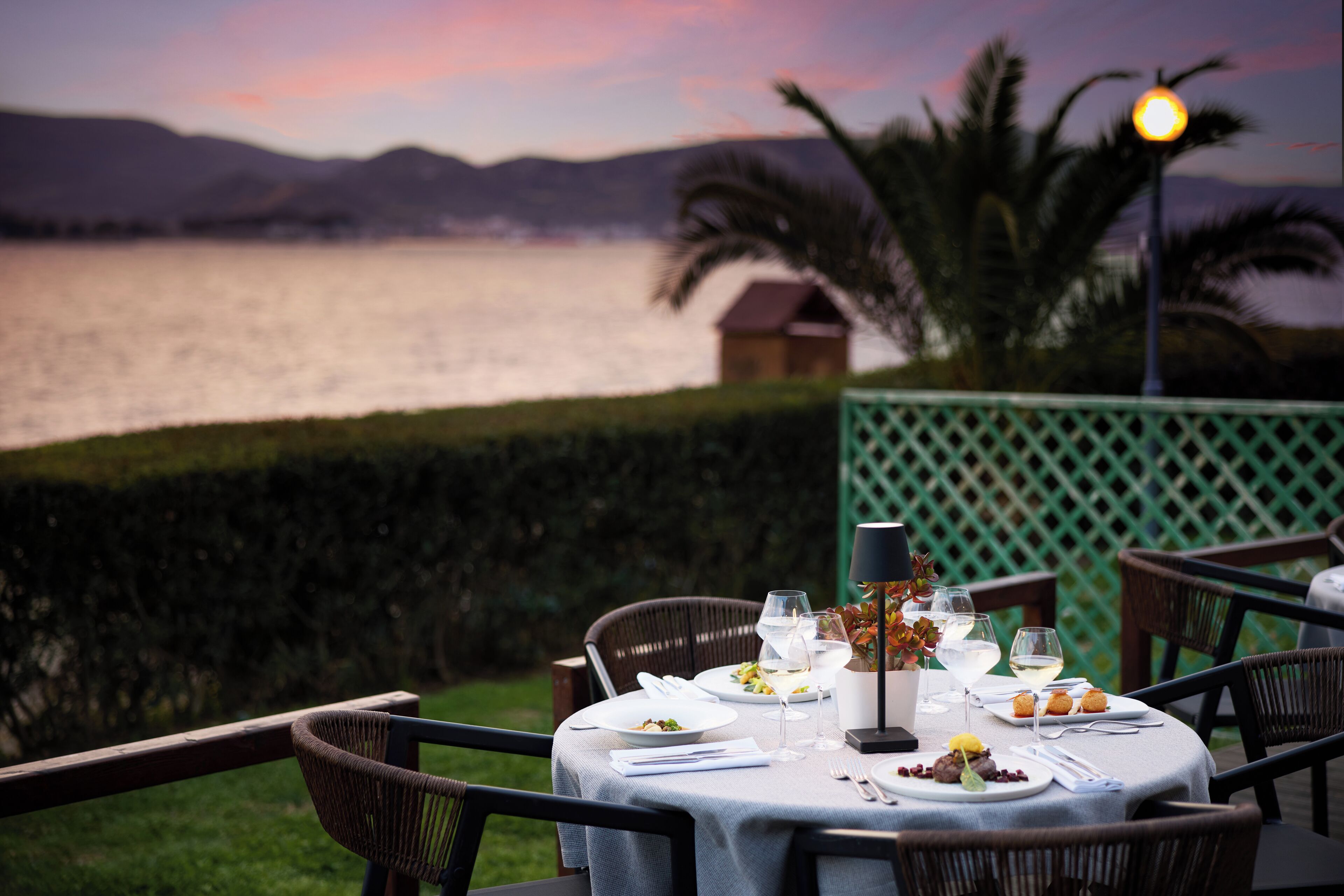 Mesa lista para una comida con vista a un lago y montañas al fondo.