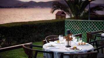 A table set for a meal with a view of a lake and mountains in the background.