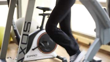 A treadmill with a person using it, a stationary bike, and a yellow exercise ball in the background.