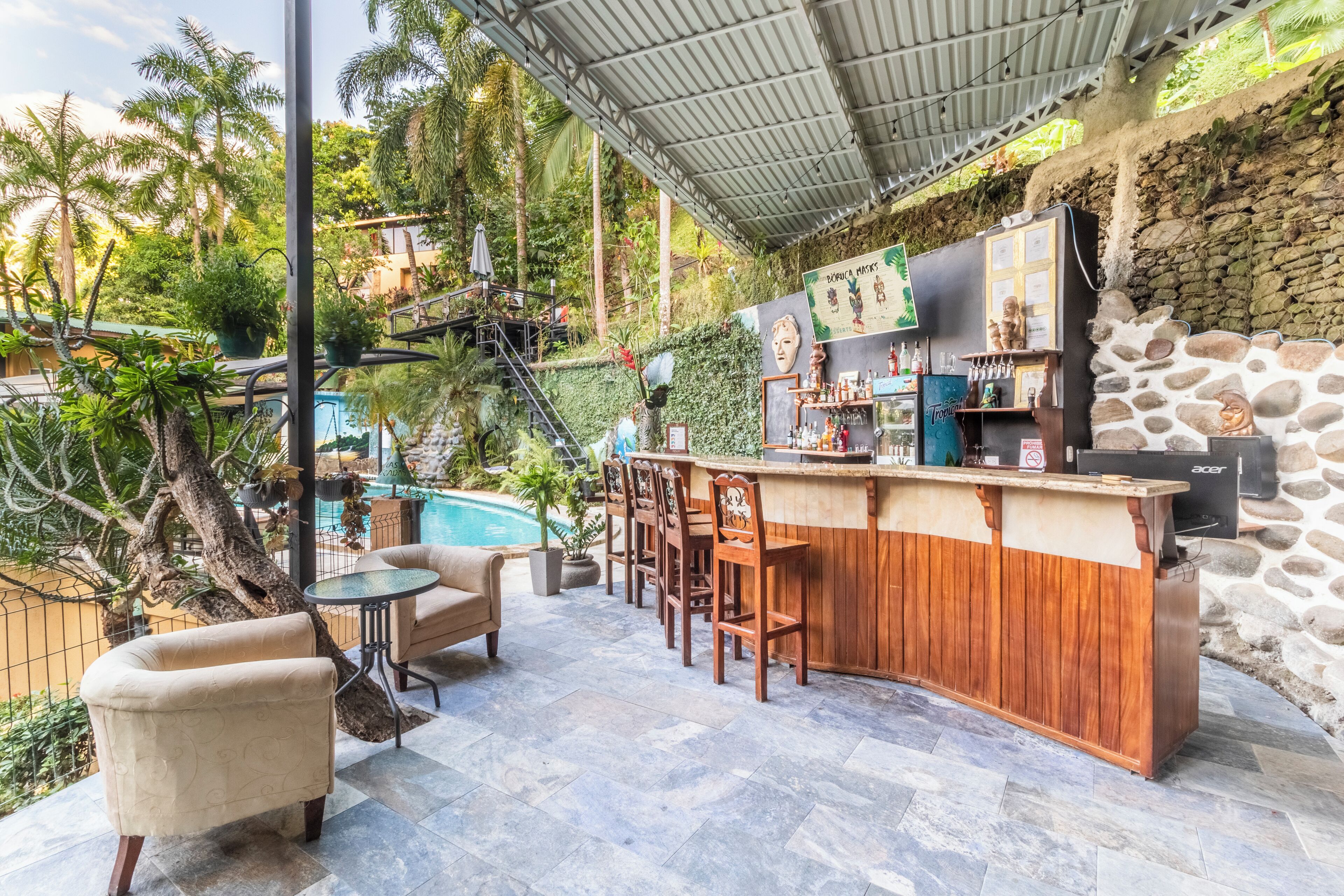 An outdoor bar area with a pool, wooden bar counter, and seating.