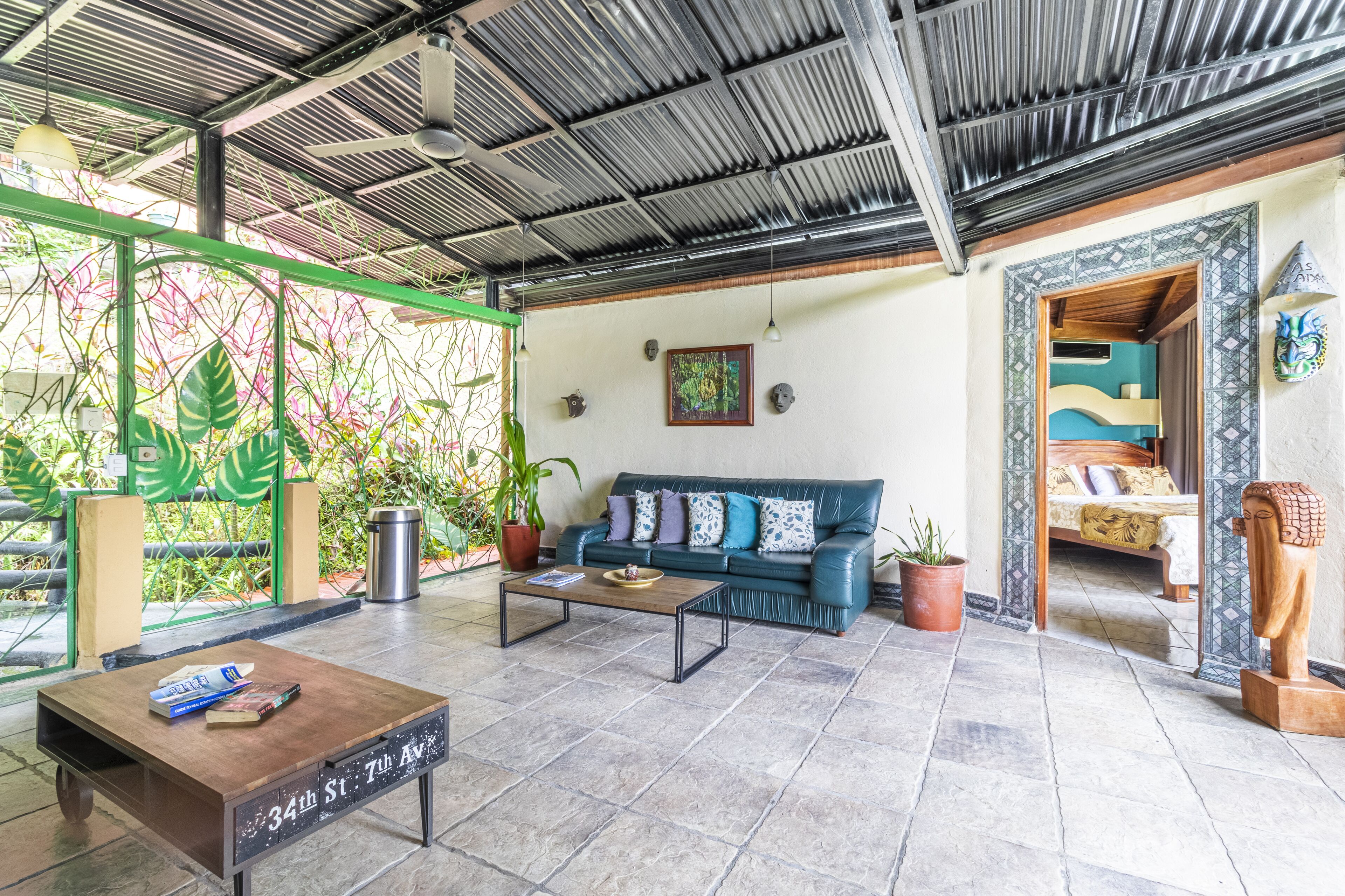 A spacious living area with a green sofa, a wooden coffee table, and a view of a bedroom through an open doorway.