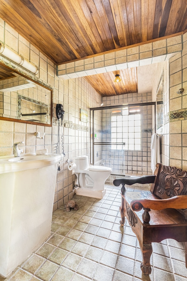 A bathroom with a wooden ceiling, a bathtub, a toilet, and a bench.