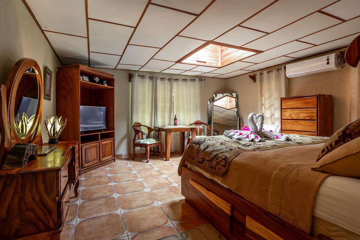 Une chambre à coucher comprenant un lit, un bureau, une chaise, un téléviseur, une armoire et un miroir.