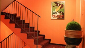 A staircase with a metal railing, a potted plant, and a poster on the wall. - Hotel Villette (Zürich)