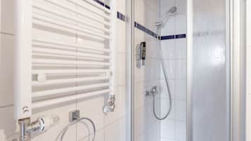 A bathroom with a glass shower enclosure, a white radiator, and a towel ring.