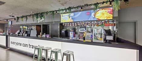 A food counter with a neon sign, a digital menu, and a cash register.