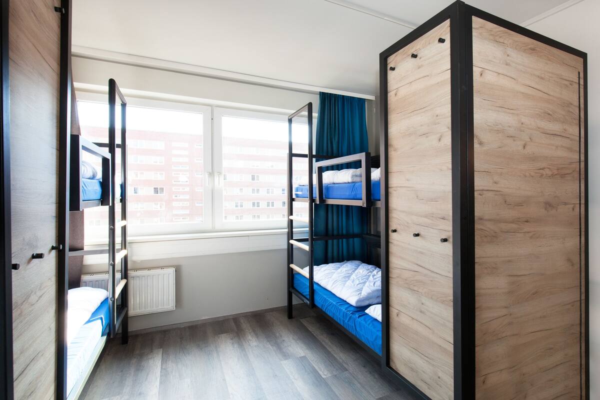 Una habitación con literas, una ventana y un radiador.