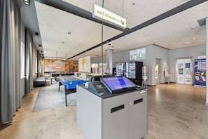 A self-check-in kiosk, a foosball table, and a large window with a view.
