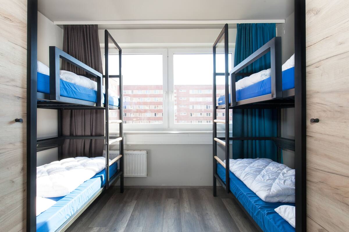 A room with bunk beds, a window with curtains, and a radiator.