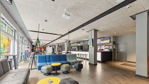 Un área de lounge moderna con asientos, bar y una escalera.