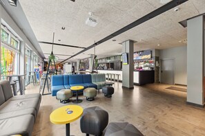 A modern lounge area with seating, a bar, and a staircase. - a&o Berlin Hauptbahnhof (Berlin)