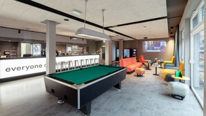 Una mesa de billar en un moderno área de lounge con barra y asientos.