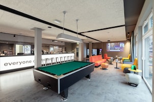 Una mesa de billar en un moderno área de lounge con barra y asientos.
