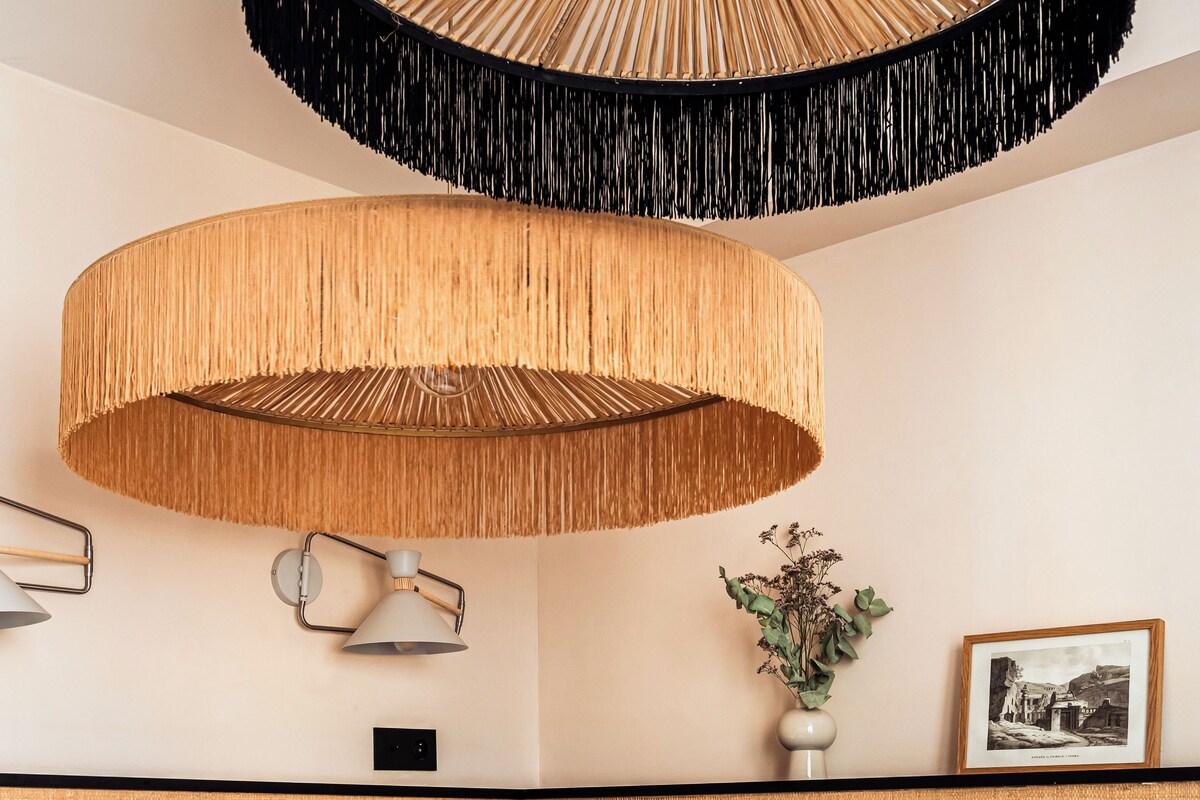 Une chambre d’hôtel avec un lit, une lampe fixée au mur, un tableau encadré et une petite plante en pot.