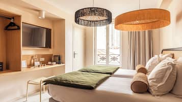 Un dormitorio moderno con una cama, un banco, un televisor, un escritorio y dos lámparas colgantes.