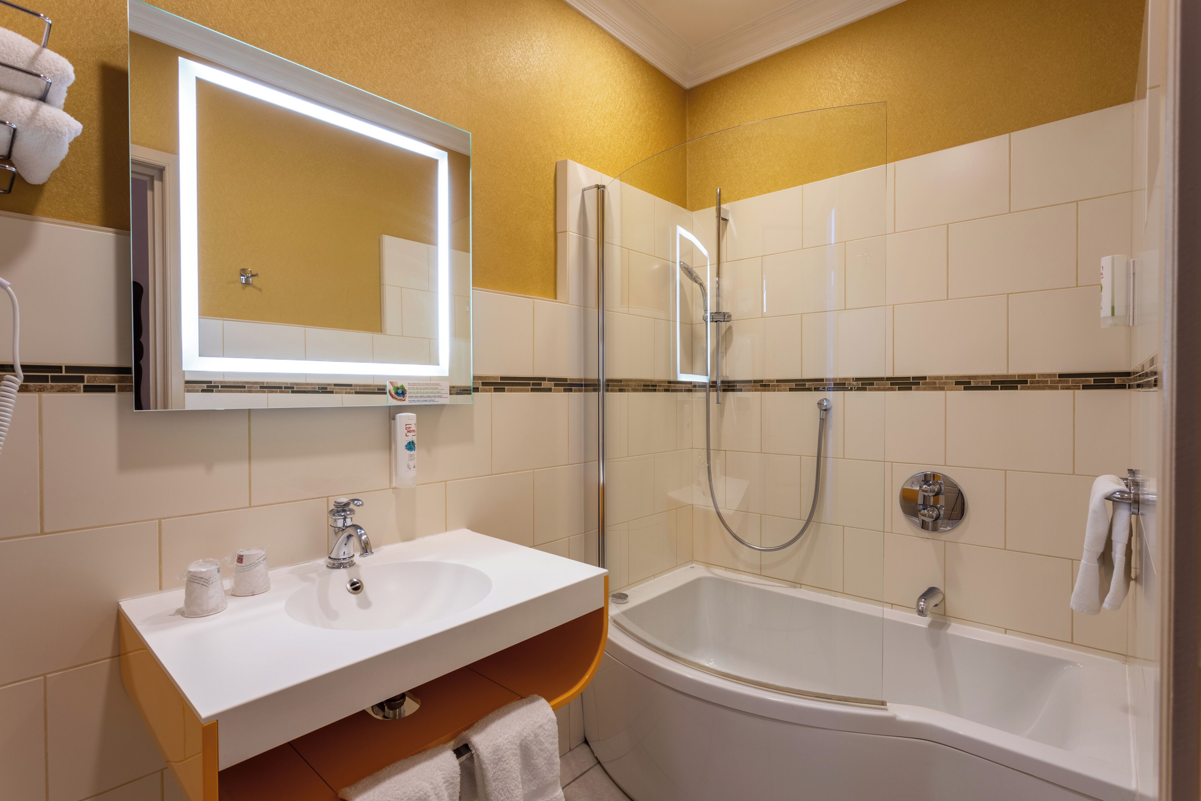 Un baño con lavamanos blanco, espejo y bañera.