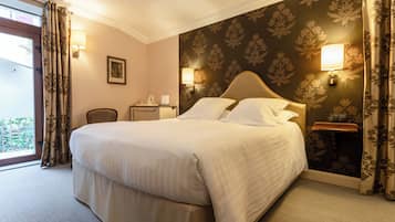 Une chambre d’hôtel avec un grand lit, deux lampes de chevet, une table de chevet, une chaise et une fenêtre avec des rideaux.