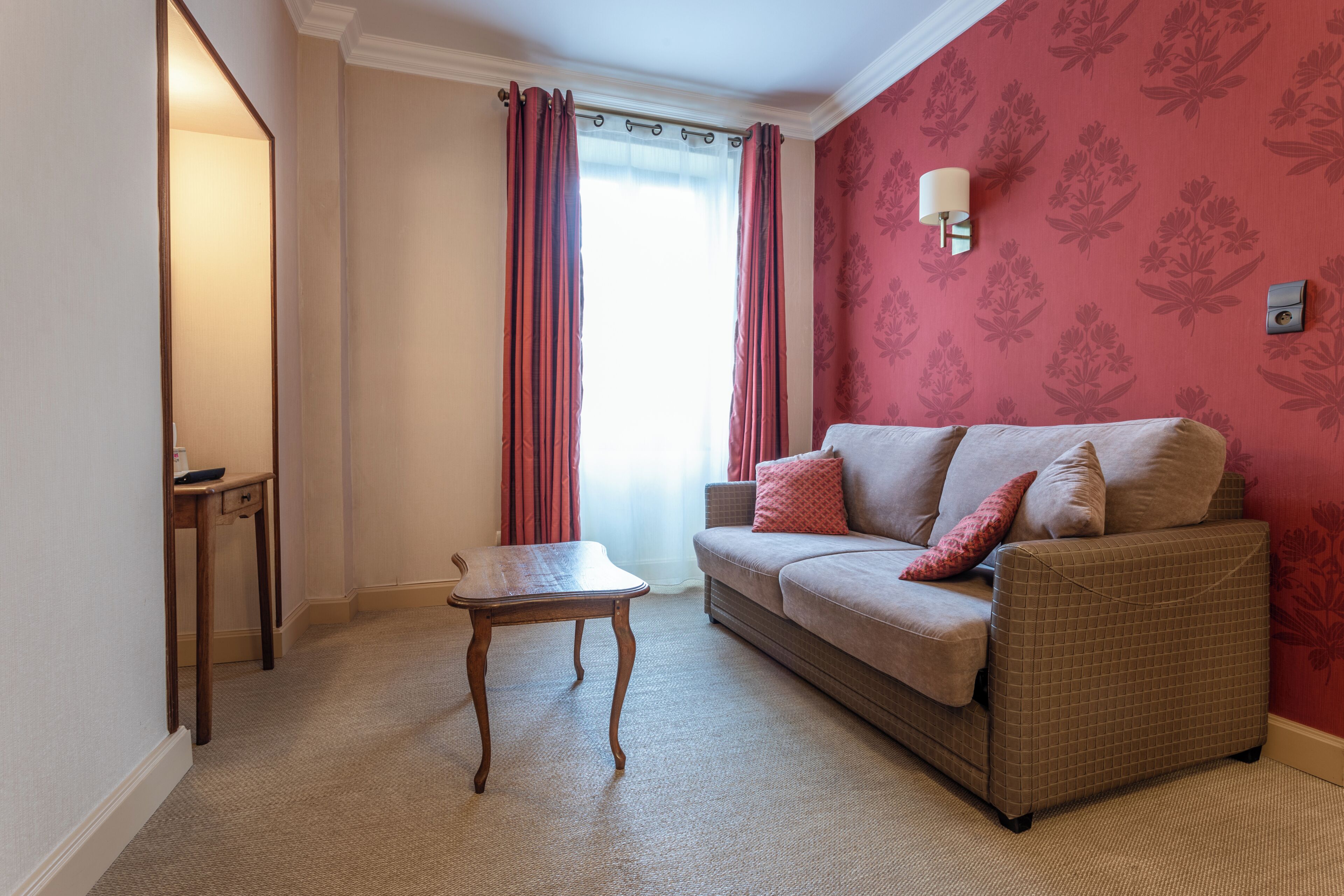 A living room with a sofa, a small table, and a window with curtains.