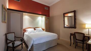Une chambre d’hôtel avec un grand lit, deux chaises, un bureau et un miroir.