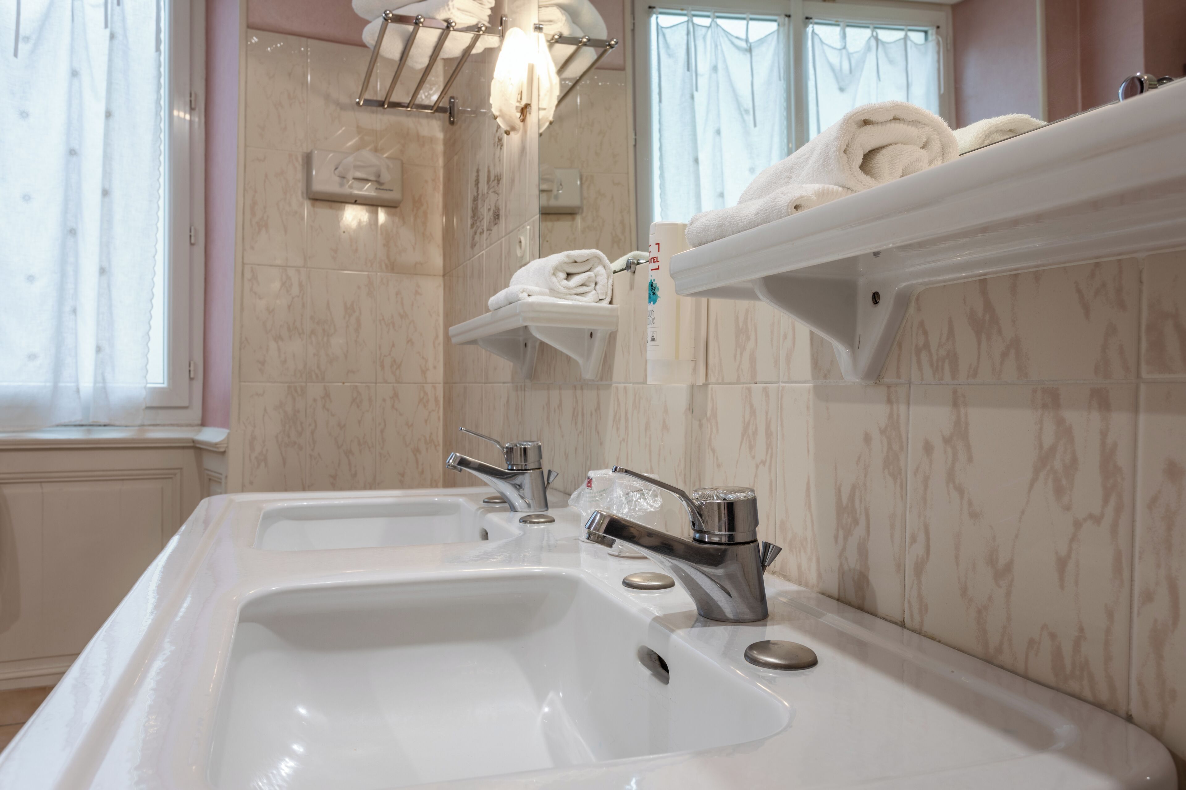 Un baño con dos lavamanos, un espejo y un perchero para toallas.