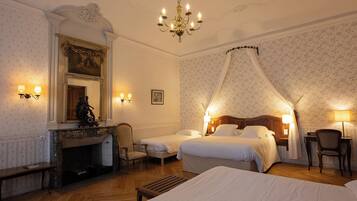 Habitación de hotel con chimenea, dos camas, dosel sobre la cama y un escritorio con una silla.