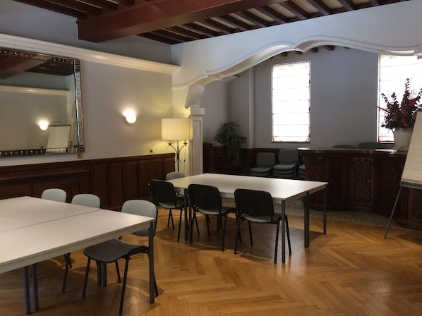 Una sala conferenze con un lungo tavolo, diverse sedie, un grande specchio e una finestra con vista sull'esterno.