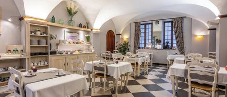 A dining area with checkered flooring, white tables, and chairs.