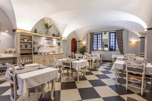 A dining area with checkered flooring, white tables, and chairs. - Citotel Le Sphinx (Montélimar)