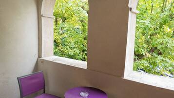 A room with two arched windows, a purple chair, a purple table, and a small table.