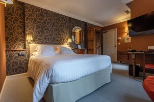 Habitación de hotel con una cama grande, un escritorio, un armario y un televisor.