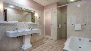 Une salle de bain avec un grand lavabo, un miroir, une douche et une baignoire.