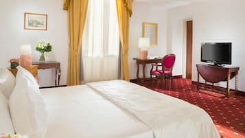 Una habitación de hotel con una cama grande, un escritorio con una silla, un televisor y una ventana con cortinas.
