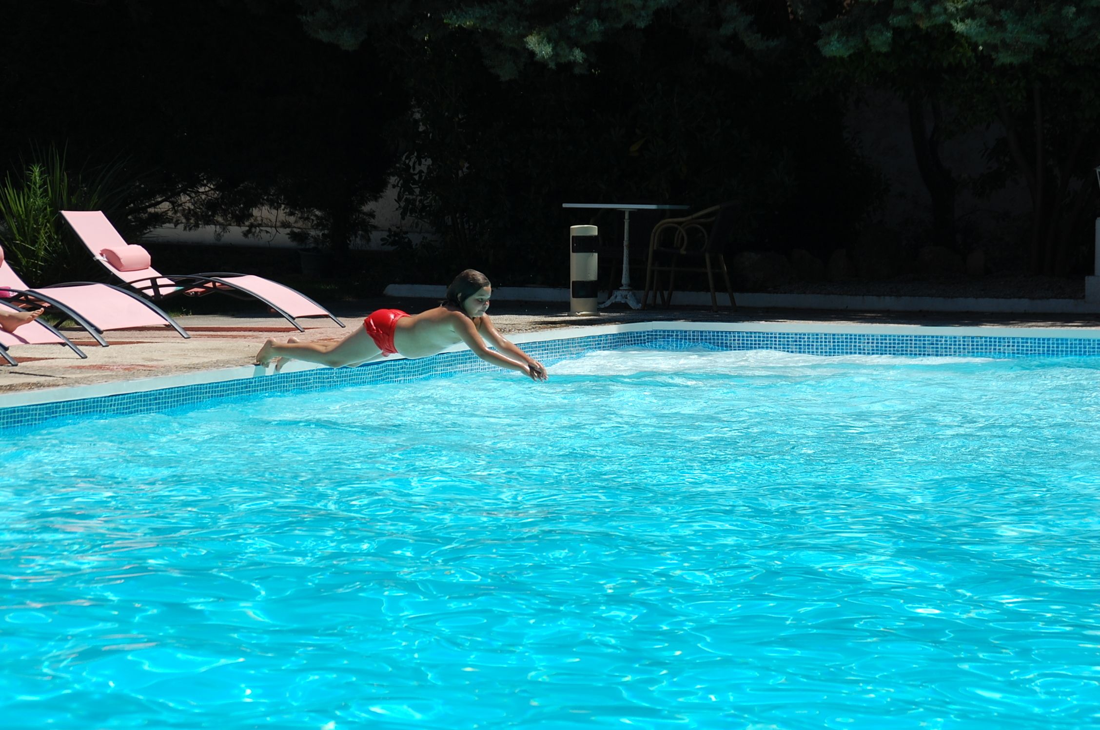 A swimming pool with a person in a red swimsuit swimming.
