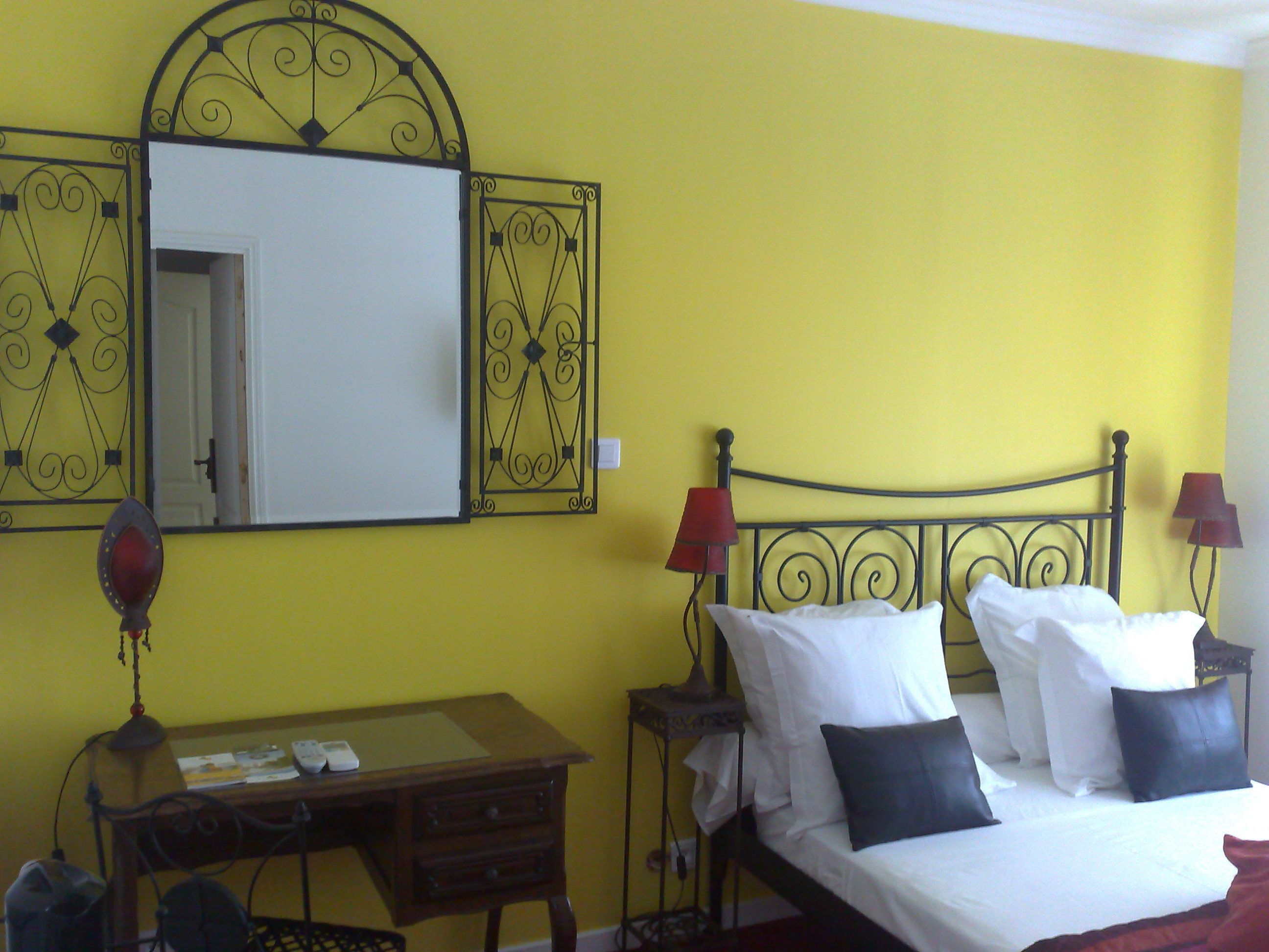 Une pièce avec un lit, un bureau et un miroir au mur.