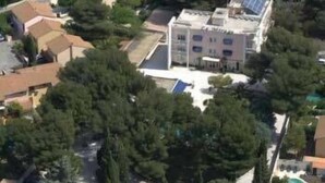 An aerial view of a residential area with a prominent building featuring solar panels, surrounded by dense trees and neighboring houses. - Citotel Le Mirage (Istres)