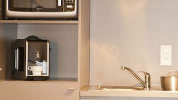 Una cocina moderna con microondas, cafetera y pileta con grifo.