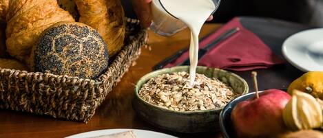 Un desayuno con pan, un tazón de cereal y un vaso de leche.