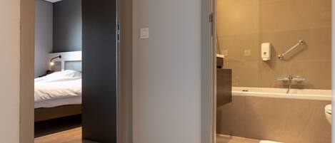A modern bathroom with a bathtub, shower, and toilet.