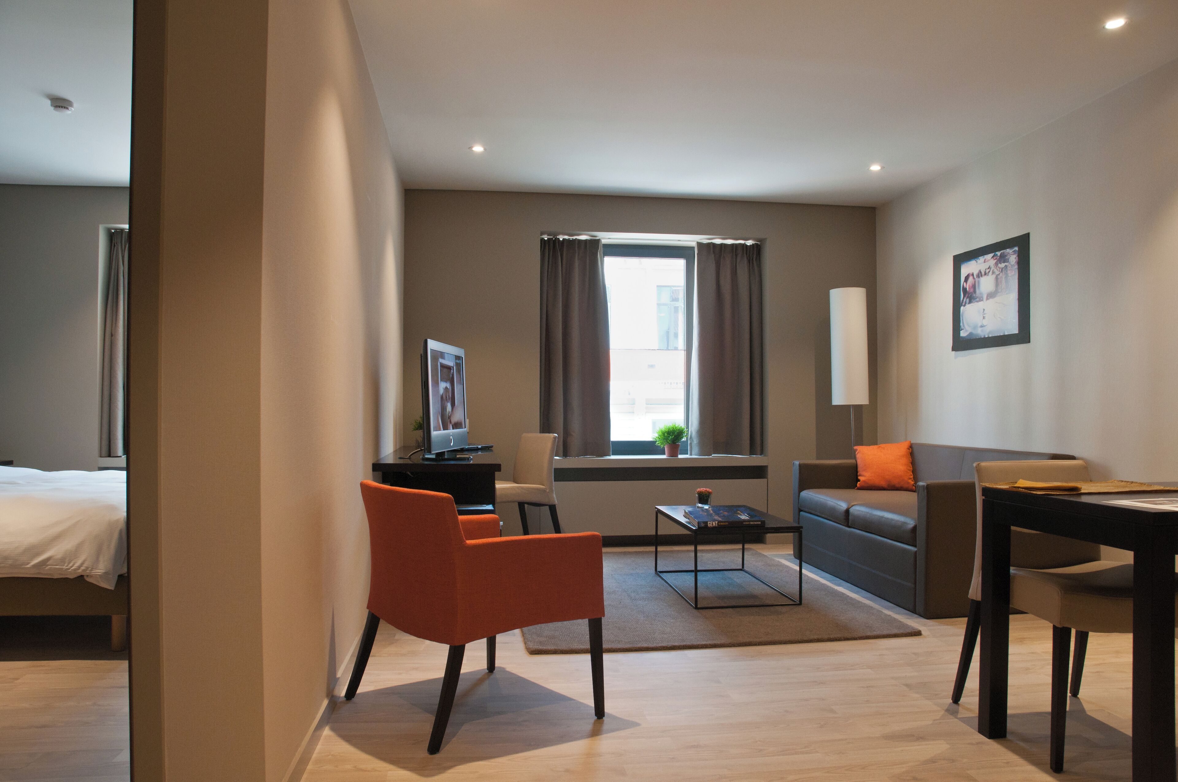 Una habitación de hotel moderna con una cama, un sofá, una mesa de comedor y un televisor.