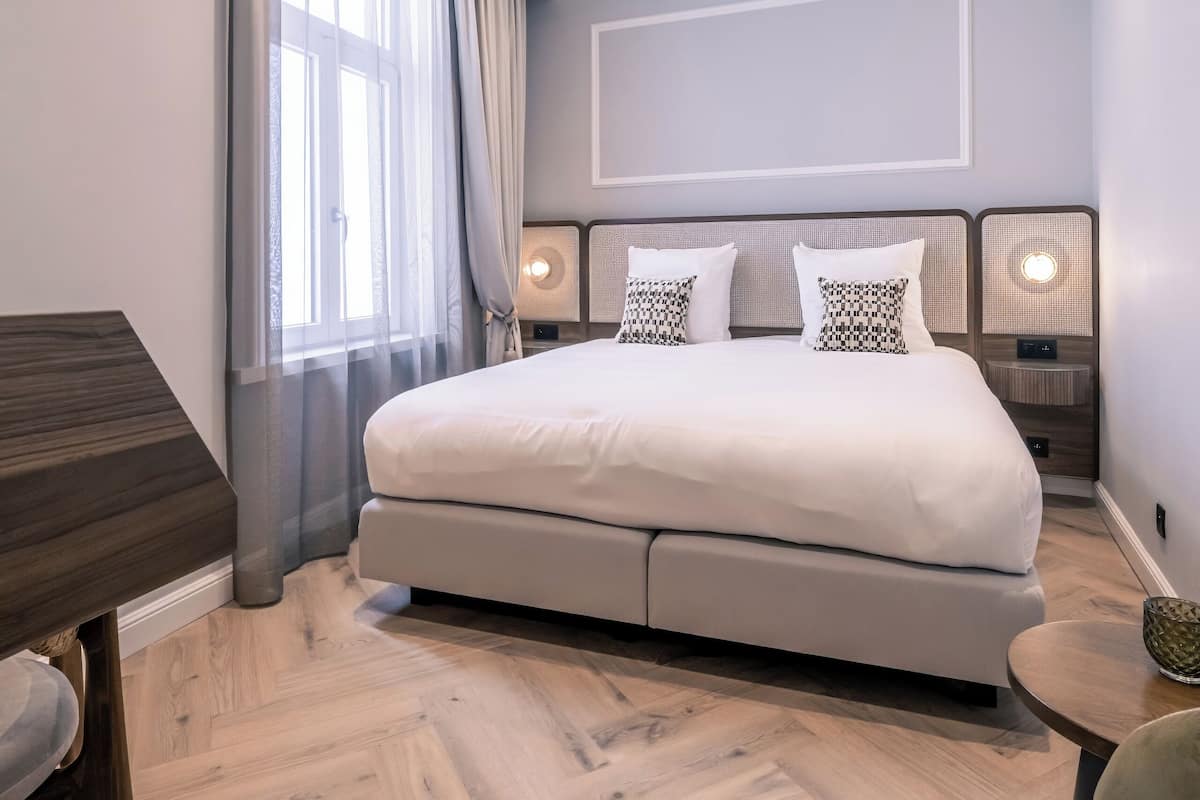A modern hotel room with a large bed, a desk, and a chair.