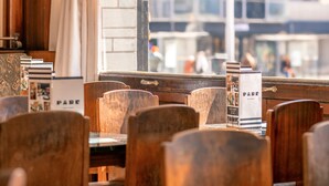 L’intérieur d’un restaurant avec des chaises en bois, un vitrail et une vue sur un bâtiment à l’extérieur.