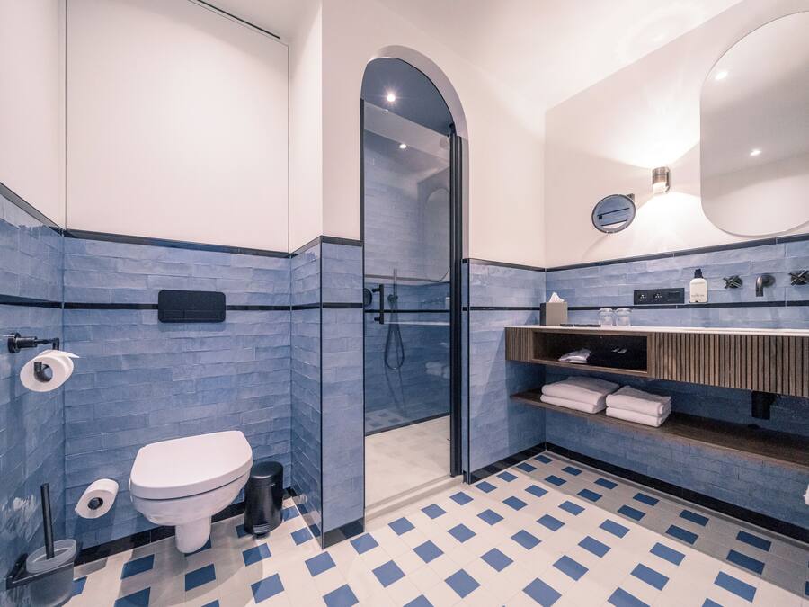 A modern bathroom with a glass-enclosed shower, a white toilet, and a blue-tiled floor.