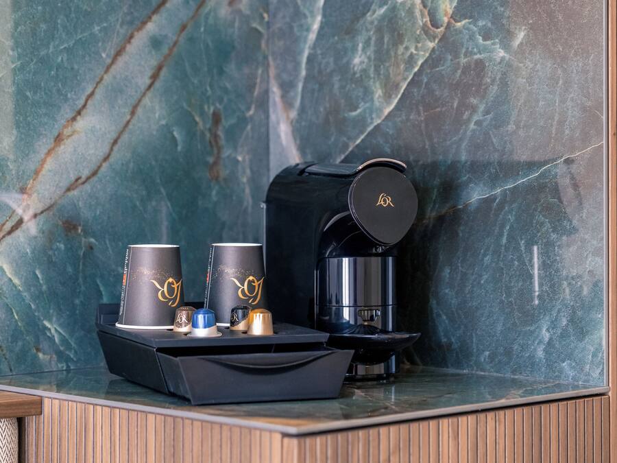 A marble countertop with a coffee maker, two cups, and a small tray.