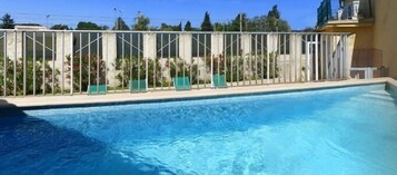 Una piscina al aire libre, sombrillas, sillones reclinables de piscina