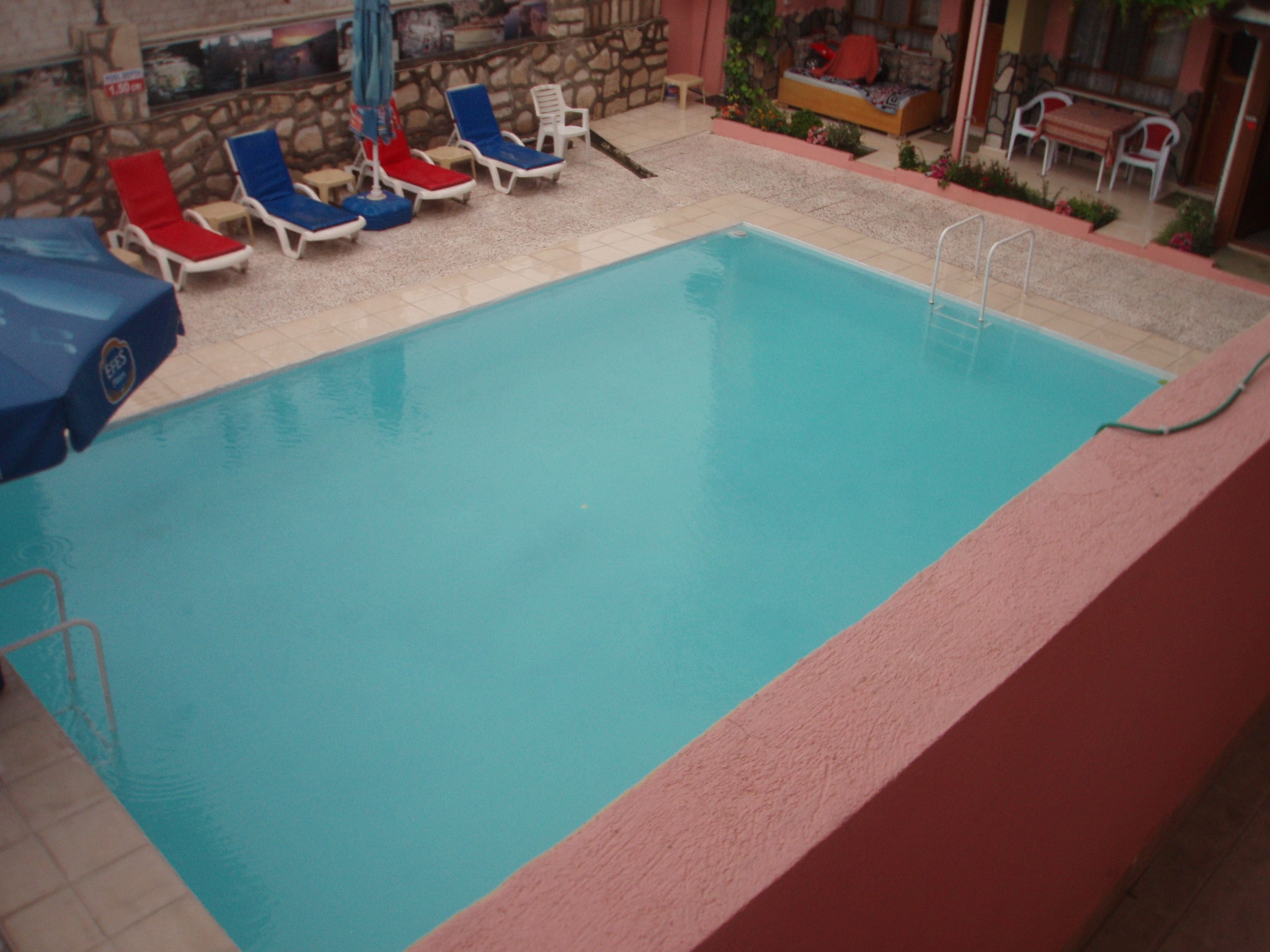 An indoor swimming pool with lounge chairs and a stone wall.