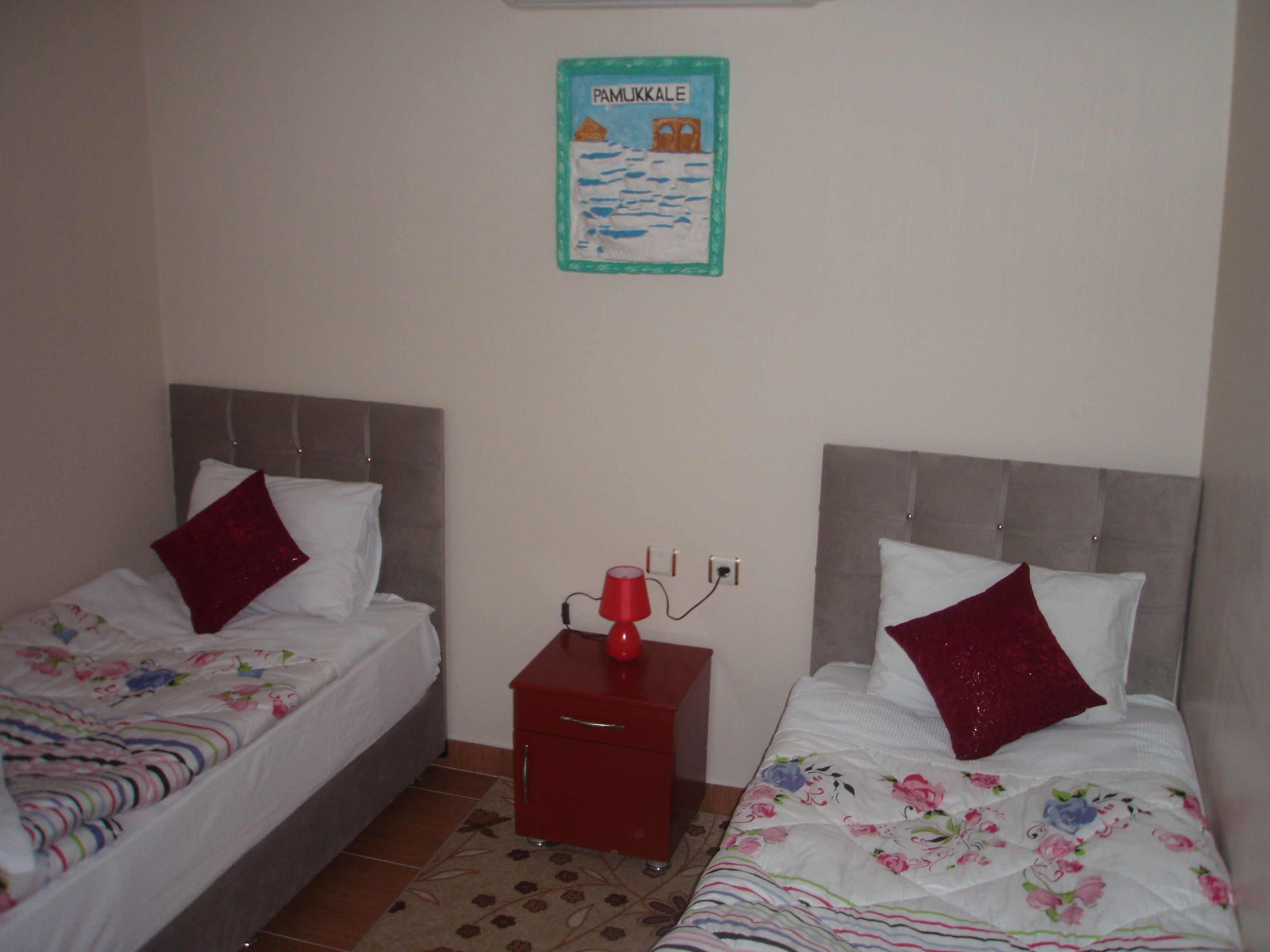 A twin room with two beds, a nightstand, and a wall poster.