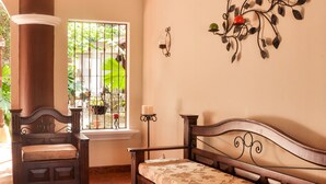 Una habitación con un banco de madera, un sofá, un adorno en la pared y una ventana con vistas a la vegetación.